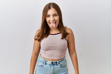Obraz premium Young brunette woman standing over isolated background sticking tongue out happy with funny expression. emotion concept.