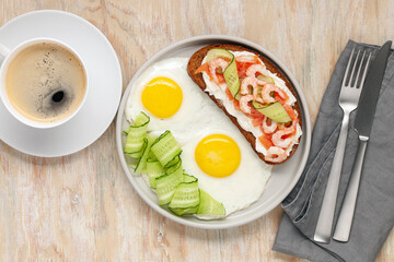 Sandwich with cheese, cucumber and shrimp, fried eggs on a plate and coffee on the table. Healthy breakfast. Top View