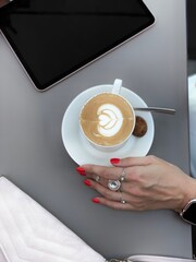 hand holding a cup of coffee on lunch brake with iPad and purse