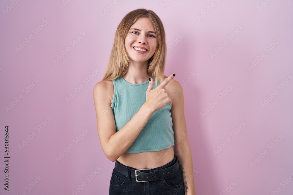 Sticker blonde caucasian woman standing over pink background cheerful with a smile on face pointing with han