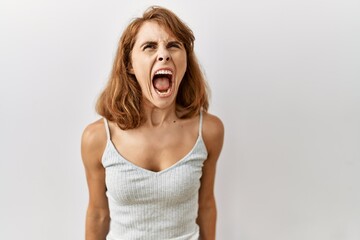 Beautiful caucasian woman standing over isolated background angry and mad screaming frustrated and furious, shouting with anger. rage and aggressive concept.