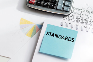 STANDARDS text on a blue card that sits on a notepad on an office desk