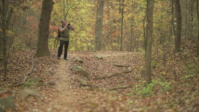 Male taking pictures with camera and exploring in the Autumn forest landscape 