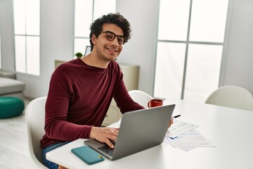 Fototapeta premium Young hispanic man using laptop working at home.