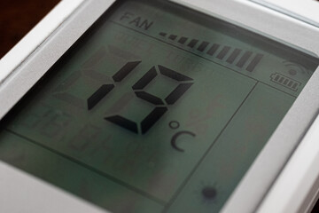 Close-up of a remote air condition with heating at 19 degrees on screen related with the price energy crisis in europe for an expensive heating costs.