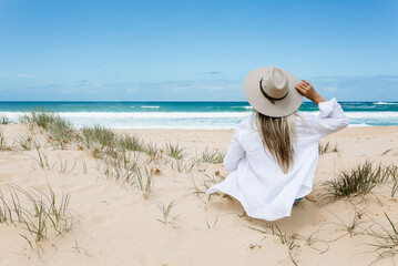 Fototapeta na wymiar Woman sits on a clean sandy beach in Australia - summertime leisure recreation travel vacation