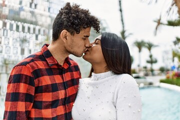 Obraz premium Young latin couple kissing and hugging at the city.