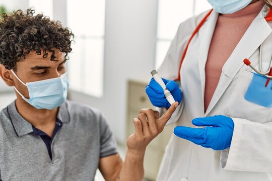 Young Latin Doctor Woman Wearing Medical Mask Measuring Gluscose At Examination Room.