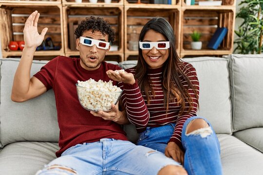Young latin couple smiling happy sitting on the sofa at home.