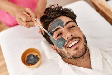 Man smiling happy reciving facial treatment at beauty center.