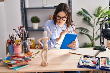 Young woman artist using touchpad drawing manikin on touchpad at art studio