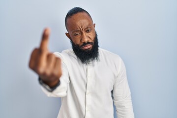 African american man standing over blue background showing middle finger, impolite and rude fuck off expression