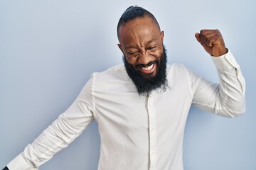 African american man standing over blue background dancing happy and cheerful, smiling moving casual and confident listening to music