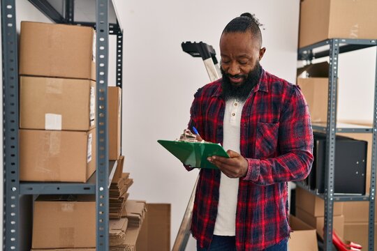 Young african american man ecommerce business worker organizing packages at office - Powered by Adobe