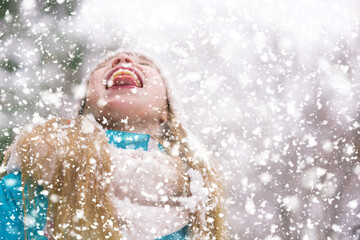 A girl kid widely opened mouth to catch the snow.