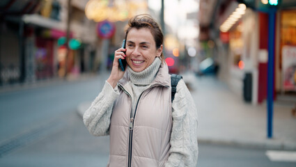 Fototapeta premium Middle age hispanic woman smiling confident talking on the smartphone at street