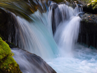 CLOSE UP: Wild mountain river flowing over mossy rocks forming small waterfalls