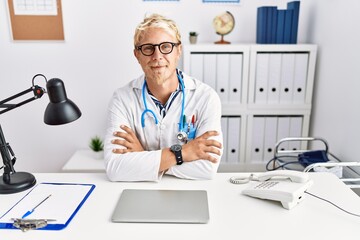 Obraz premium Young caucasian man wearing doctor uniform with arms crossed gesture at clinic