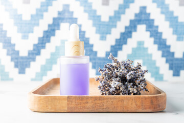 Glass bottle of Lavender essential oil with dry lavender flowers on wooden rustic tray, aromatherapy spa massage concept. Lavendula oleum