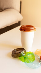 a coffee in a plastic cup on the table with lids of different colors