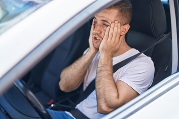 Young caucasian man stressed driving car at street