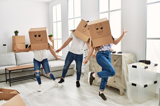 Mother and couple playing with funny cardboard box on head at home