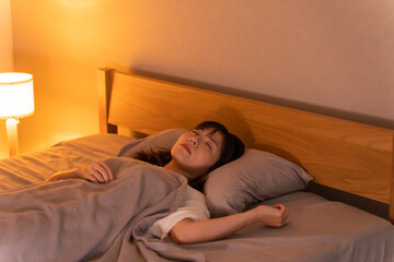 寝室のベッド寝る日本人女性 - obrazy, fototapety, plakaty