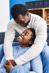 Obraz premium Man and woman couple hugging each other sitting on sofa at home