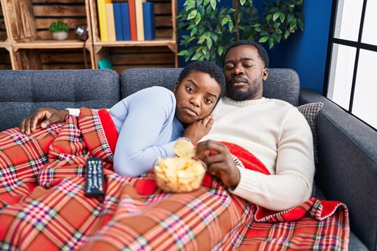 Young African American Couple Sitting On The Sofa Watching Tv Depressed And Worry For Distress, Crying Angry And Afraid. Sad Expression.