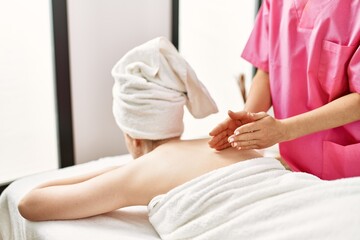 Young caucasian woman reciving back massage at beauty center.