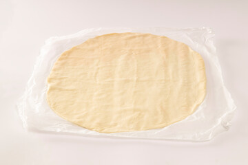 Pizza dough on baking paper on white background