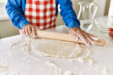 Senior man keading pizza dough at kitchen