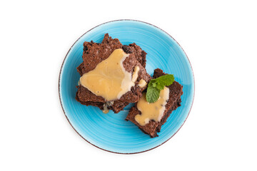 Chocolate brownie with caramel sauce isolated on white, top view, close up.
