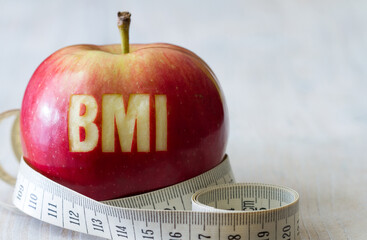 Red apple with text BMI and measuring tape, diet and healthy weight concept 