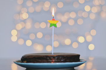 Festive birthday cake with burning candles against bright bokeh background. Greeting card. Party and holiday celebration concept.