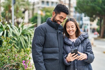 Man and woman couple smiling confident using smartphone at park