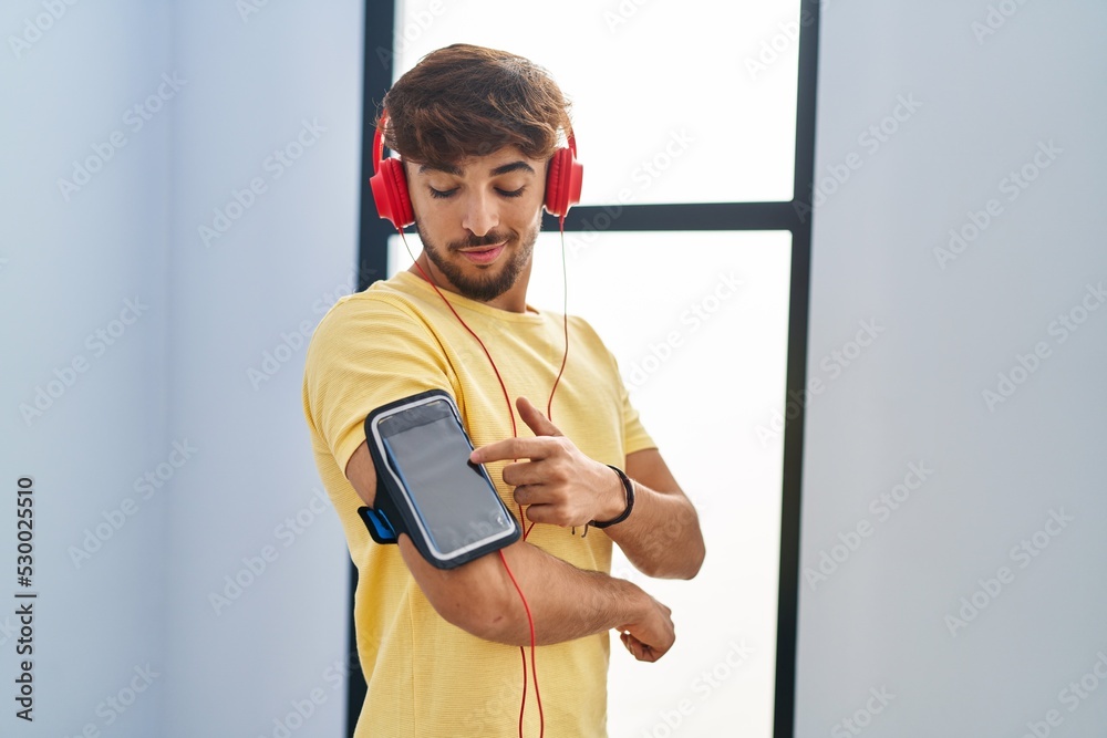 Sticker Young arab man listening to music standing at sport center