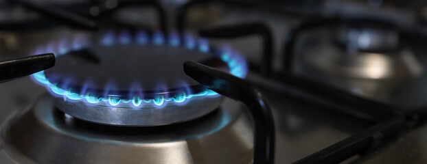 Banner of a close-up of a flame of methane gas stove in a domestic kitchen.