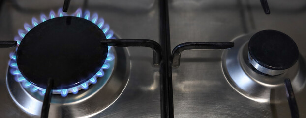 Banner of a close-up of a flame of methane gas stove in a domestic kitchen.
