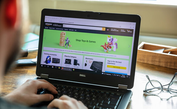 AMAZON. com. App, shop toys and games, Amazon UK, pc on blur office desk, hand on keyboard.