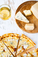 Pizza quattro formaggi on a wooden board .four cheese pizza and fresh ingredients for a four cheeses Italian pizza on a white wooden desk .