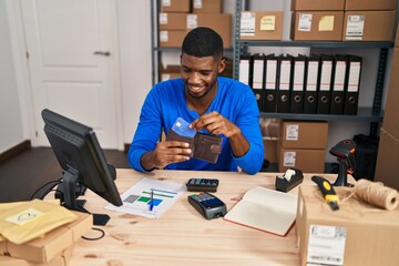 Young african american man ecommerce business worker holding wallet with credit card at office