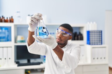 Young african american man wearing scientist uniform holding test tube at laboratory © Krakenimages.com
