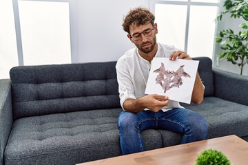 Obraz premium Young hispanic man doing rorschach test at psychology session at clinic