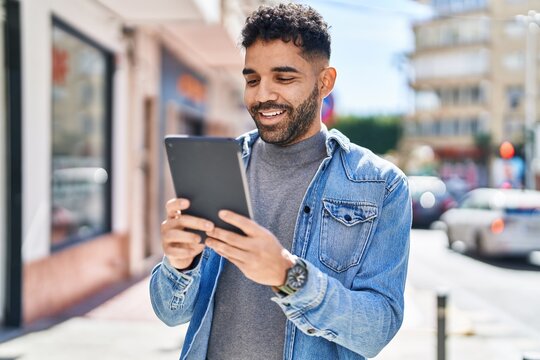 Young hispanic man smiling confident using touchpad at street