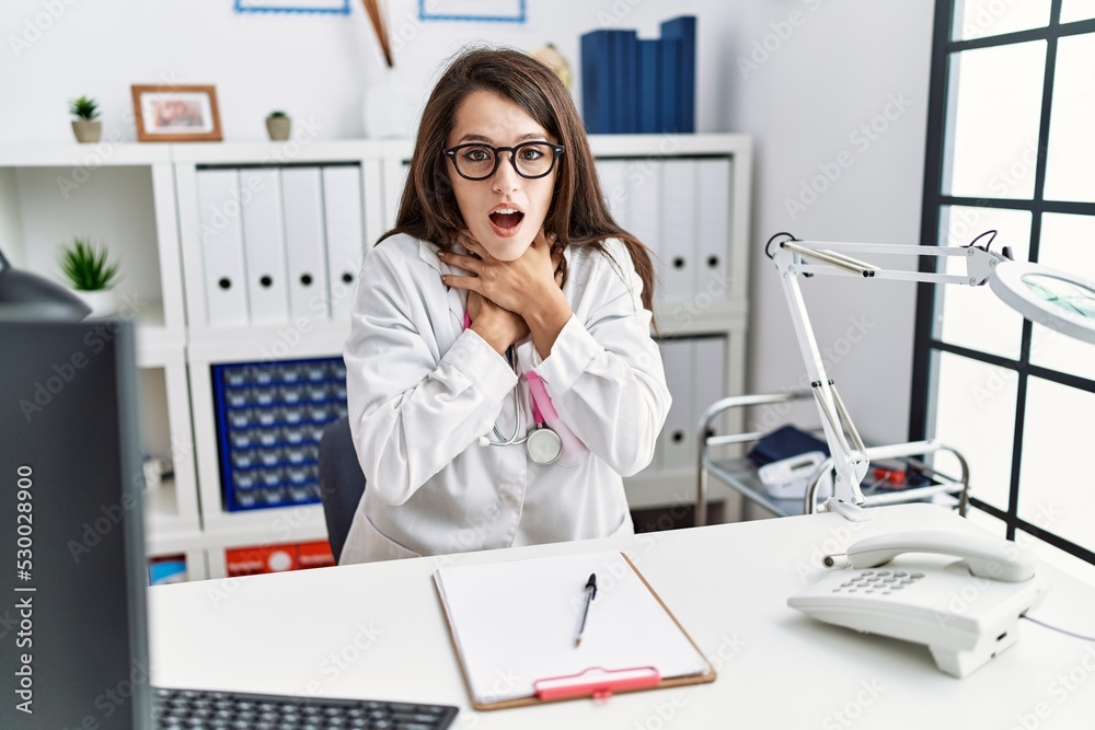 Wall mural Young doctor woman wearing doctor uniform and stethoscope at the clinic shouting and suffocate because painful strangle. health problem. asphyxiate and suicide concept.