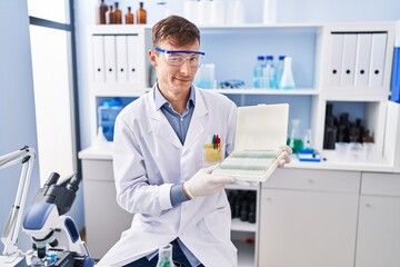 Caucasian man working at scientist laboratory winking looking at the camera with sexy expression,...