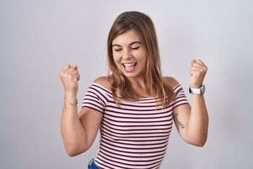 Young hispanic woman standing over isolated background very happy and excited doing winner gesture with arms raised, smiling and screaming for success. celebration concept.