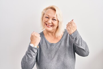 Middle age caucasian woman standing over white background very happy and excited doing winner gesture with arms raised, smiling and screaming for success. celebration concept.