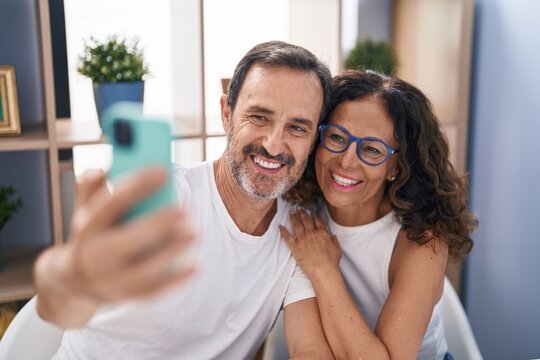 Man and woman couple make selfie by smartphone sitting on table at home